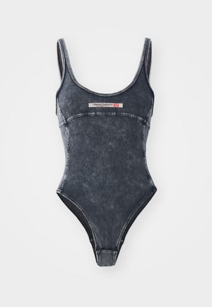 Maillot de bain une pièce en denim bleu foncé avec une texture délavée. Doté de bretelles étroites et d'un patch logo à l'avant. Jambes à taille haute.