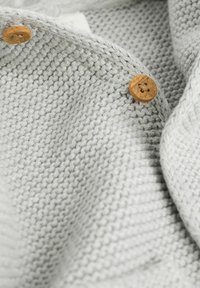 Gray knitted fabric with a textured pattern. Two wooden buttons with a cross-stitch detail are visible, enhancing the design.