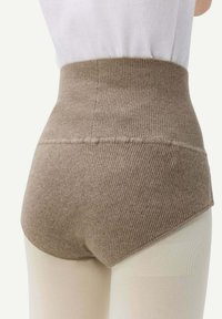 Höga, stickade shorts i en varm taupefärg, med ribbad textur och en slät midjeresår. Accentuerade med ljusbruna leggings.