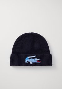 Gorro de lã azul-marinho com uma dobra na barra; apresenta um logo de crocodilo bordado em azul e vermelho na frente. Tecido texturizado.