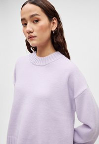 Ανοιχτό μωβ πλεκτό πουλόβερ με ριμπ ύφασμα στον λαιμό και χαλαρή εφαρμογή. Μαλακή υφή με κατεβασμένους ώμους και μακριά μανίκια.