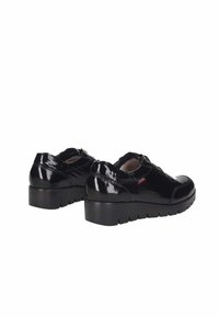 Zapatos de charol negros con puntera redonda, cierre de cordones, suela de plataforma gruesa y sutiles acentos rojos en los laterales.