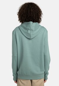Sudadera con capucha en color verde agua claro, hecha de una tela suave. Presenta un bolsillo tipo canguro y puños con textura de canalé. Se muestra la vista trasera.