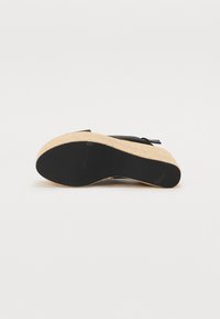 Svart lær fotbed sandal med korkkile såle, teksturert finish og en løkkeaksel på den øvre delen. Flatt svart gummisåle.