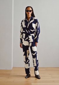 Navy and cream patterned shirt and pants set, made of a smooth fabric with a relaxed fit; features a collared shirt and an elastic waistband.
