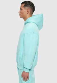 Mintgrüner Hoodie, weicher Stoff, lässige Passform, große Kapuze, Kängurutasche, gerippte Bündchen und Saum, glatte Textur, minimale Designdetails.