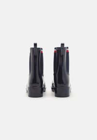 Czarne lakierowane botki Chelsea z elastycznymi bocznymi panelami, czerwonymi i niebieskimi paskami akcentującymi oraz teksturowanym materiałem, z pętelkami do łatwego zakładania.