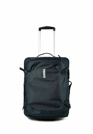 Black Thule soft-sided luggage with telescoping handle and compression straps on a white background.