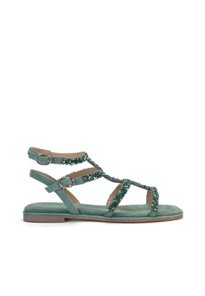 Sandale en daim vert avec des sangles décoratives en perles, deux boucles ajustables à la cheville, semelle plate et design de bout légèrement arrondi.