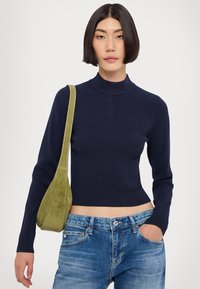 Pull à col roulé côtelé bleu marine avec manches longues, design court, associé à un jean bleu clair et un sac à épaule en daim vert.