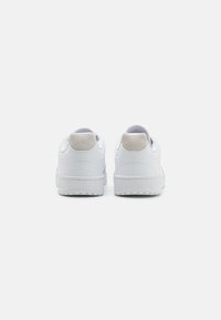 Hvide lædersneakers med en tekstureret suede hælaccent, der har en polstret krave, gummisål og minimalistisk design.