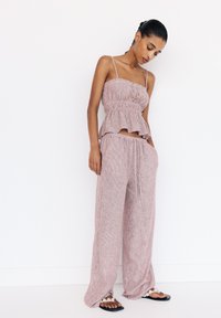 Two-piece outfit featuring a sleeveless, ruffled peplum top and wide-leg pants in a pink-striped fabric, with a relaxed fit and drawstring waist.