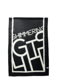 Schwarze Decke mit weicher Textur und weißen Blockbuchstaben, die "SHIMMERING GIFT" schreiben. Geometrische Muster und Logoakzent am Rand.