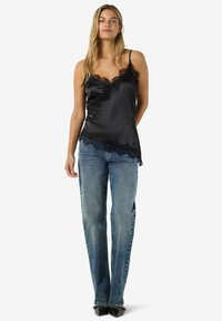 Mustast satiinist kammisool pitsist ääristusega, õhukeste rihmadega, kombineeritud helesiniste sirge säärega teksade ja mustade teravate varvastega jalanõudega.