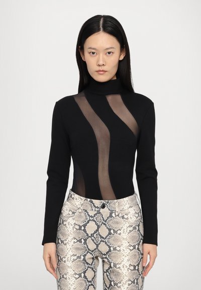 Body noir à manches longues avec des panneaux transparents créant des formes courbes ; associé à un pantalon ajusté beige à imprimé serpent, avec des accents de tissu texturé.