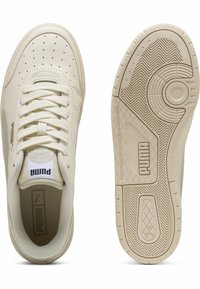 Pantofii sport PUMA din piele crem au un vârf perforat, șireturi plate și o talpă din cauciuc texturată cu un logo pe lateral.