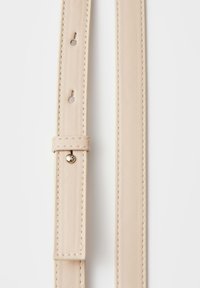 Cintura in pelle sintetica beige con bordi cuciti, multiple perforazioni circolari e una fibbia rotonda in metallo su sfondo bianco.