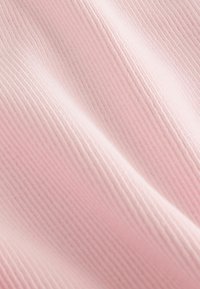 Tessuto rosa tenue a coste con sottili righe verticali e pieghe leggere che creano ombre delicate e texture.