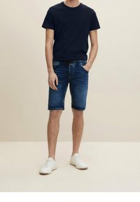 Navy cotton t-shirt paired with light blue denim shorts. The shorts feature a drawstring waistband and are slightly above the knee. White sneakers.