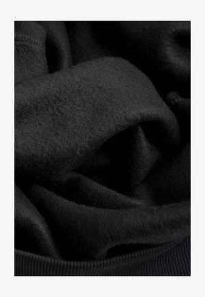 Zwarte fleece-stof met een zachte, gestructureerde oppervlakte. Het materiaal is licht gekreukeld en toont een gladde, geribbelde rand.