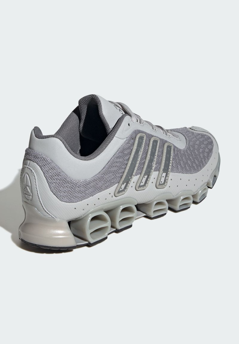 Grå atletiksko med mesh-overdel, plastdetaljer og unik polstret sål. Har tre sidestiber og polstret krave for støtte.