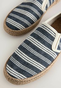 Marineblauwe en witte gestreepte espadrilles met een geweven jute zool en elastische zijkanten voor gemakkelijke instap. Gladde canvas bovenkant.
