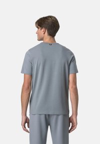 T-shirt grigio a maniche corte con scollatura rotonda e tessuto testurizzato, caratterizzato da un piccolo accento nero e giallo nella parte posteriore del collo.