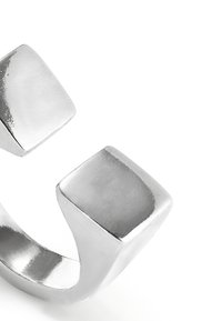 Anillo abierto de plata maciza con dos extremos planos y cuadrados en un diseño moderno y minimalista sobre un fondo blanco.