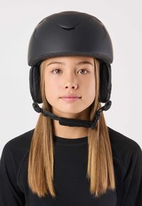 Zwarte helm met ventilatiesleuven en gevoerde oorkappen, bevestigd met een kinbandje. Draagt een persoon met recht, lichtbruin haar.