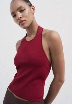 Red halter top with a fitted design, ribbed texture, and a high neckline. Smooth fabric, no visible patterns or hardware.