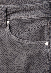 Grå leopardprint denim med en glat tekstur. Har en forlomme, kontrastsyninger og sølvfarvede hardware-detaljer.