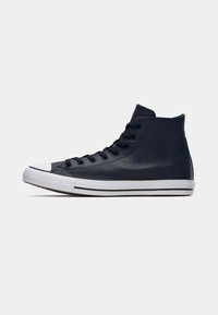 Adidași înalți din piele bleumarin, cu capac și talpă din cauciuc alb, având șireturi negre și accente contrastante albe.