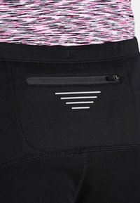 Schwarze Sportleggings mit einer Reißverschlusstasche auf der Rückseite, elegantem Design und einem strukturierten, pink-weißen gemusterten Bund.