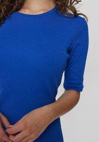Top bleu côtelé avec un col rond et des manches trois-quarts, présentant une coupe ajustée et une texture lisse.