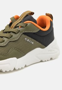 Grüne und schwarze Sneaker mit orangefarbener Innenseite, Obermaterial aus Mesh, weißer Sohle und GEox-Branding. Verfügt über eine strukturierte Oberfläche und eine Schnürverschluss.