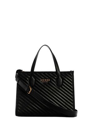 Sac à main en cuir noir matelassé avec deux poignées et une bandoulière réglable, orné du logo doré "GUESS EST 1981" sur le devant.