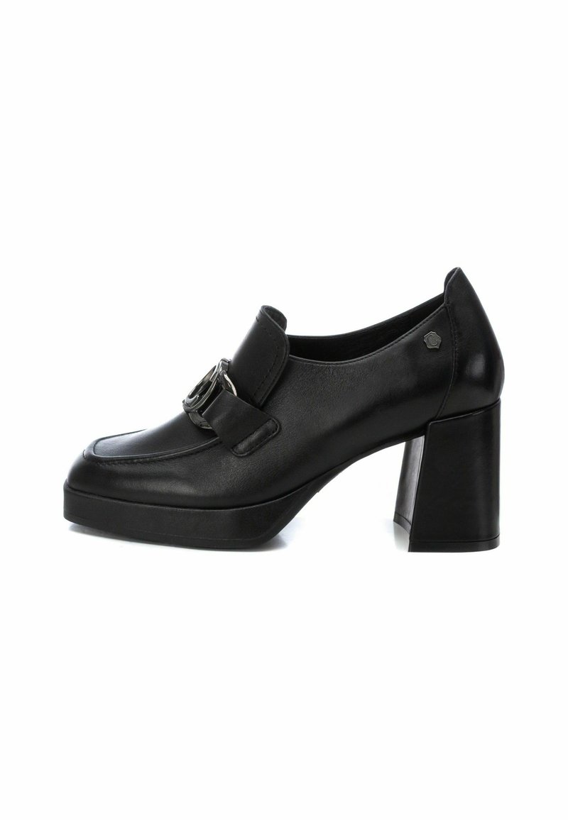 Mocassin en cuir noir pour femme avec talon haut épais et détail de boucle argentée sur fond blanc.