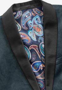 Jachetă verde închis cu un guler tip șal din satin negru. Captusită cu un model paisley în nuanțe de marin, turcoaz, maro și alb. Textură netedă.