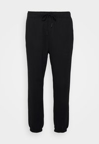 Pantaloni della tuta neri realizzati in materiale morbido con vita elastica e cordino regolabile. Dettagli alle caviglie con polsino e design leggermente affusolato.