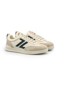 Sneakers in pelle crema con accenti in suede beige, logo verde scuro, punta arrotondata e suola in gomma testurizzata. Presentano un design con lacci e un tassello di apertura.