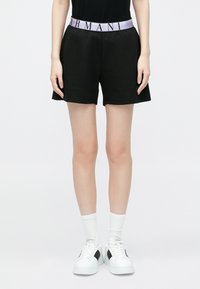 Pantaloni scurți negri cu talie elastică mov cu logo, potriviți liber și cu textură moale. Asortați cu adidași albi și șosete.