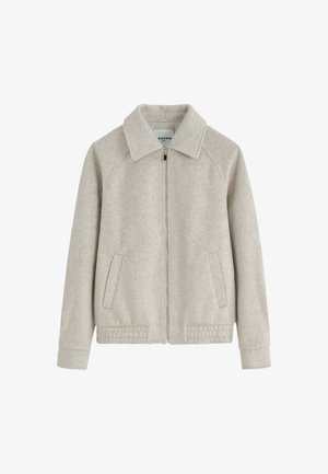 Veste en polaire beige clair avec fermeture éclair sur le devant, large col, manches longues, deux poches latérales et coutures décoratives à l'ourlet et aux poignets.