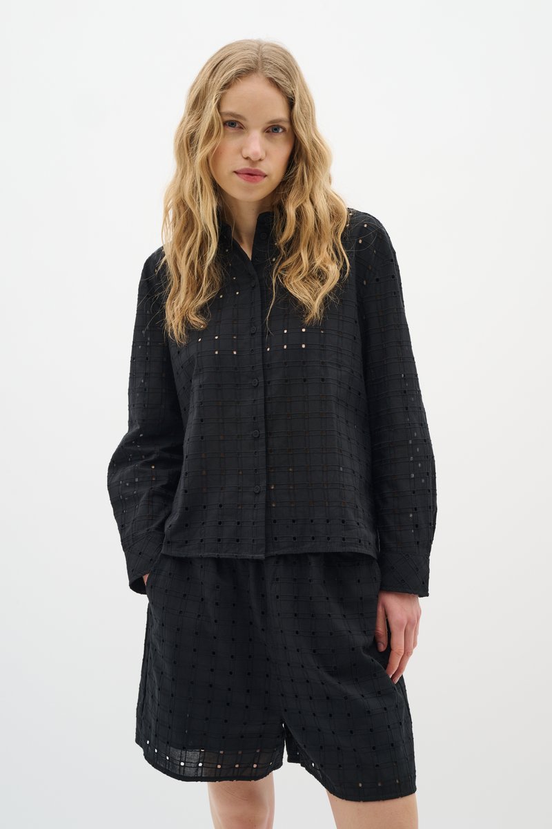 Černý bavlněný outfit s košilí na knoflíky a šortkami, který má mřížkovaný vzor s malými výřezy. Lehká textura a volný střih.