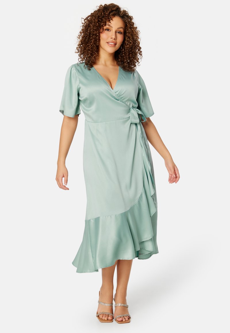 Abito avvolgente in satin verde menta morbido, con scollo a V, maniche a palloncino corte, vita legata e orlo a strati fluente.