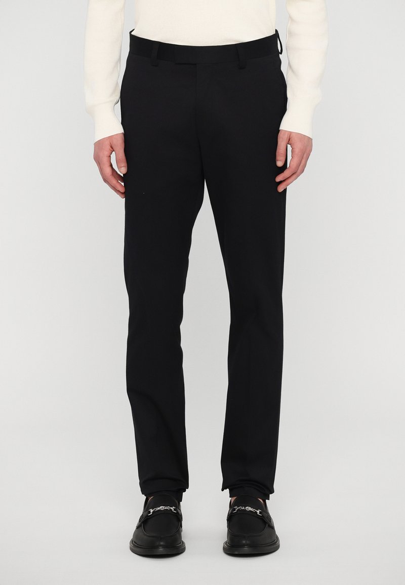 Svarta skräddarsydda byxor med slim fit, slät tyg och bältesloopar. Matchas med svarta slip-on skor med dekorativ kedjedetalj.