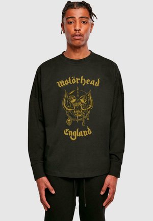 Mustapaita pitkillä hihoilla, jossa on keltainen graafinen kuvasto pääkallosta, jossa on sarvet, ja tekstinä "Motörhead England" alla.
