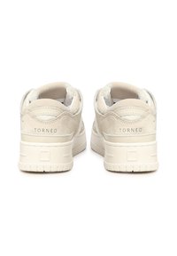 Zapatillas de ante beige con cuello acolchado y diseño bajo. Presentan el logo "TORNEO" en el talón y suela de goma texturizada.