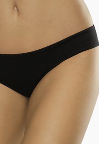 Bikini inferiore nero realizzato in tessuto liscia, con design a vita bassa e vita sottile, caratterizzato da cuciture minime per il massimo comfort.