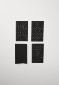 Black stickers showcasing outlines of animals, circles, and shapes on matte black surfaces, with white line details highlighting various designs.