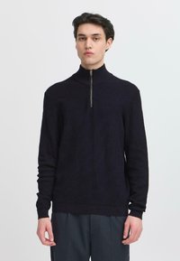 Dunkelblaues Strickpullover mit hohem Kragen und halber Reißverschluss. Verfügt über eine gerippte Textur und lange Ärmel. Glattes, enganliegendes Design.
